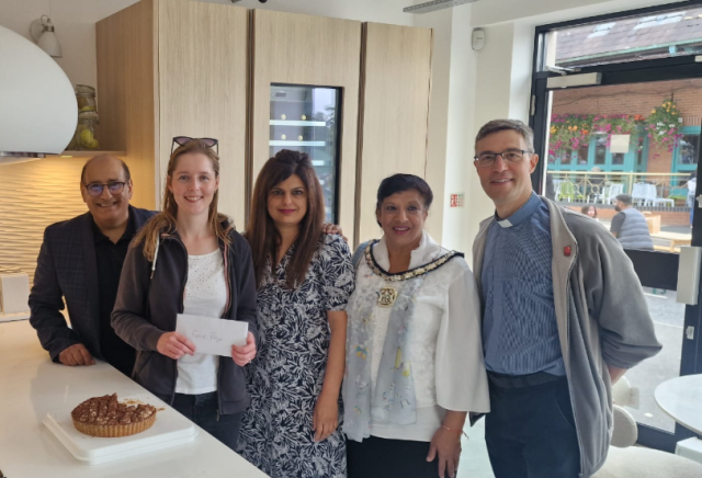 Winner of the bake off holding her prize with the judges